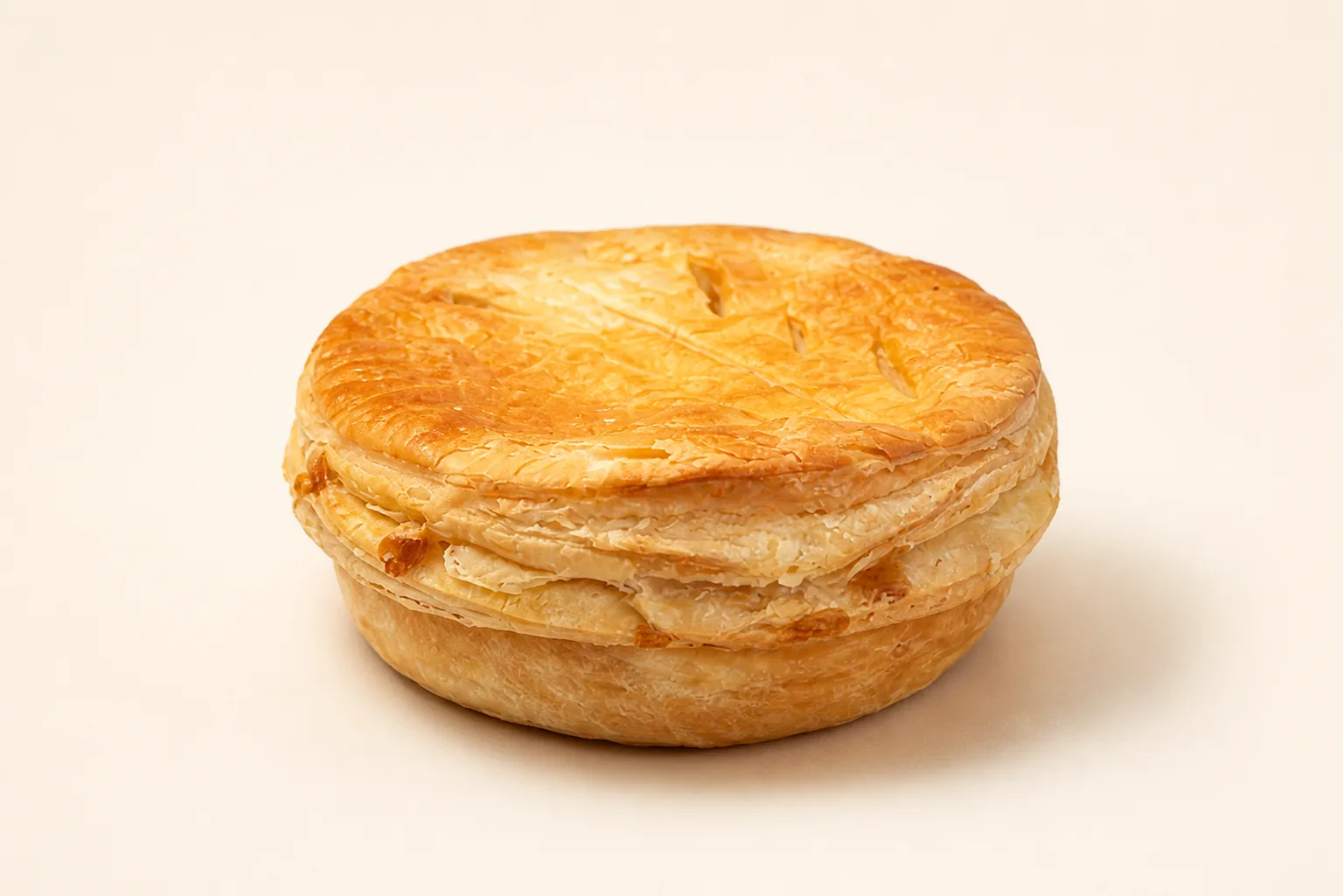 A whole golden savoury pie on a plain studio ground